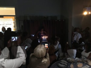 Guests taking pictures of the birthday celebrant standing behind her cake